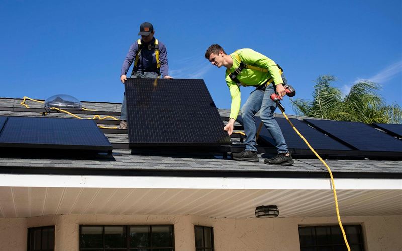 Installers fitting solar panels on a house roof